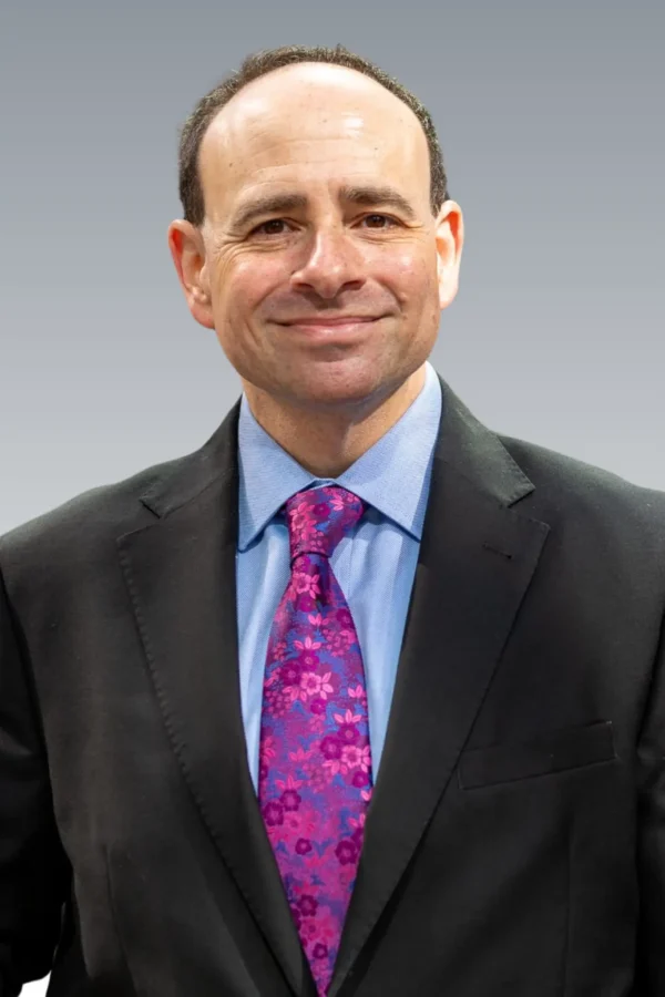 Portrait of Jordan Matyas, attorney and policy expert, in formal attire, posed in a professional office setting.