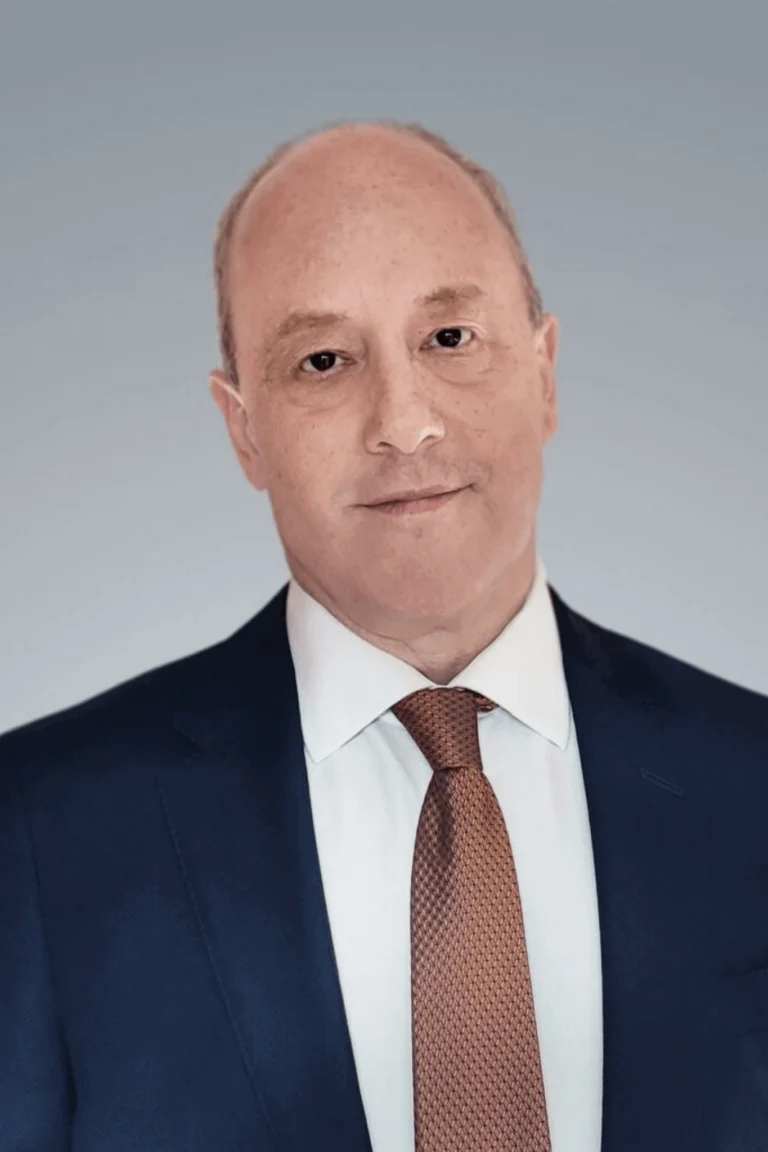 Retrato de Thomas Kanyock, abogado, con vestimenta formal de negocios, posando con confianza en un entorno legal profesional.